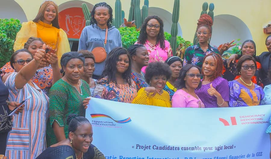 Participants holding a DRI project banner, from the Kinshasa office card