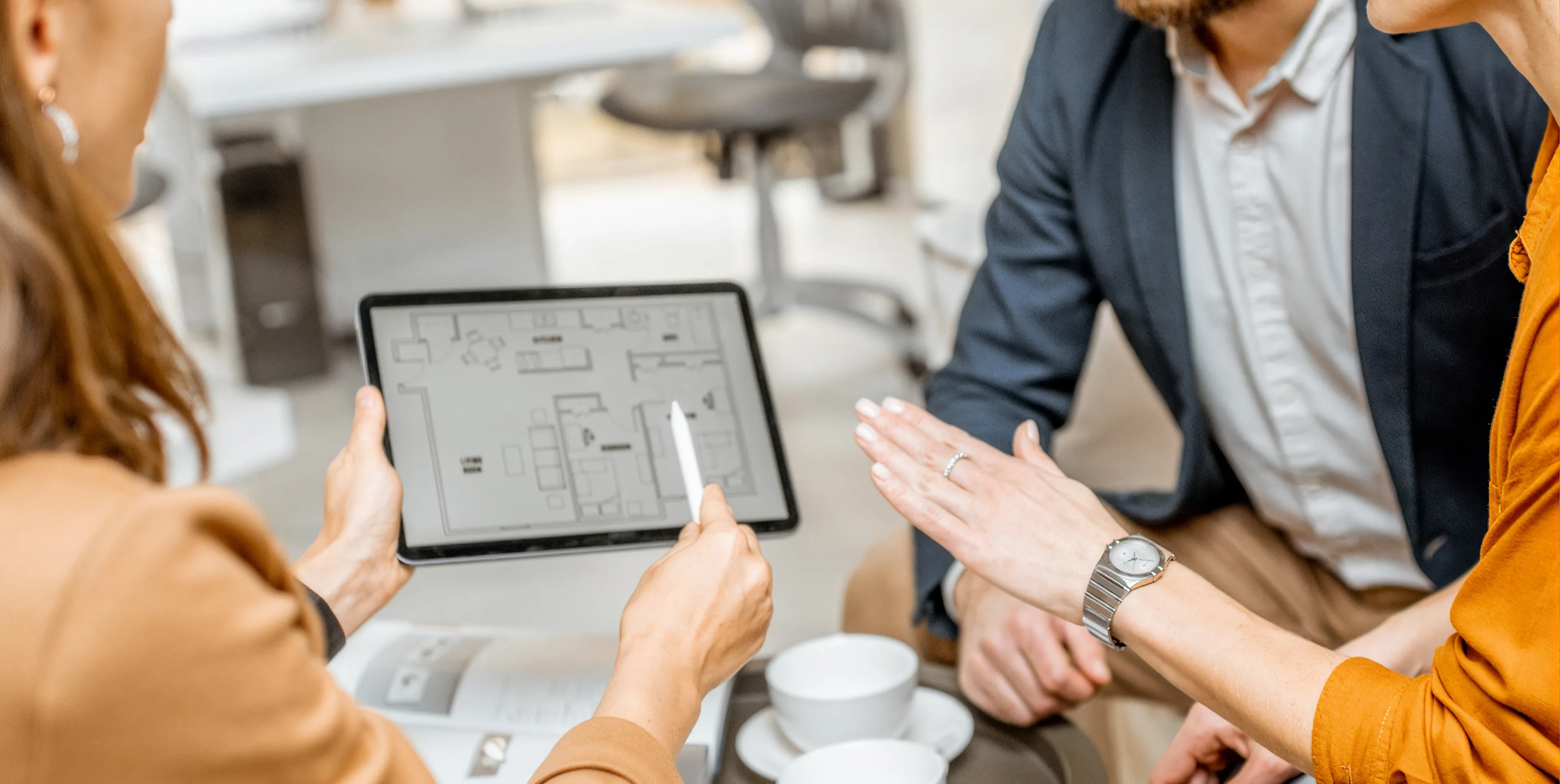 Two buyers and an agent going through a floor plan on a tablet