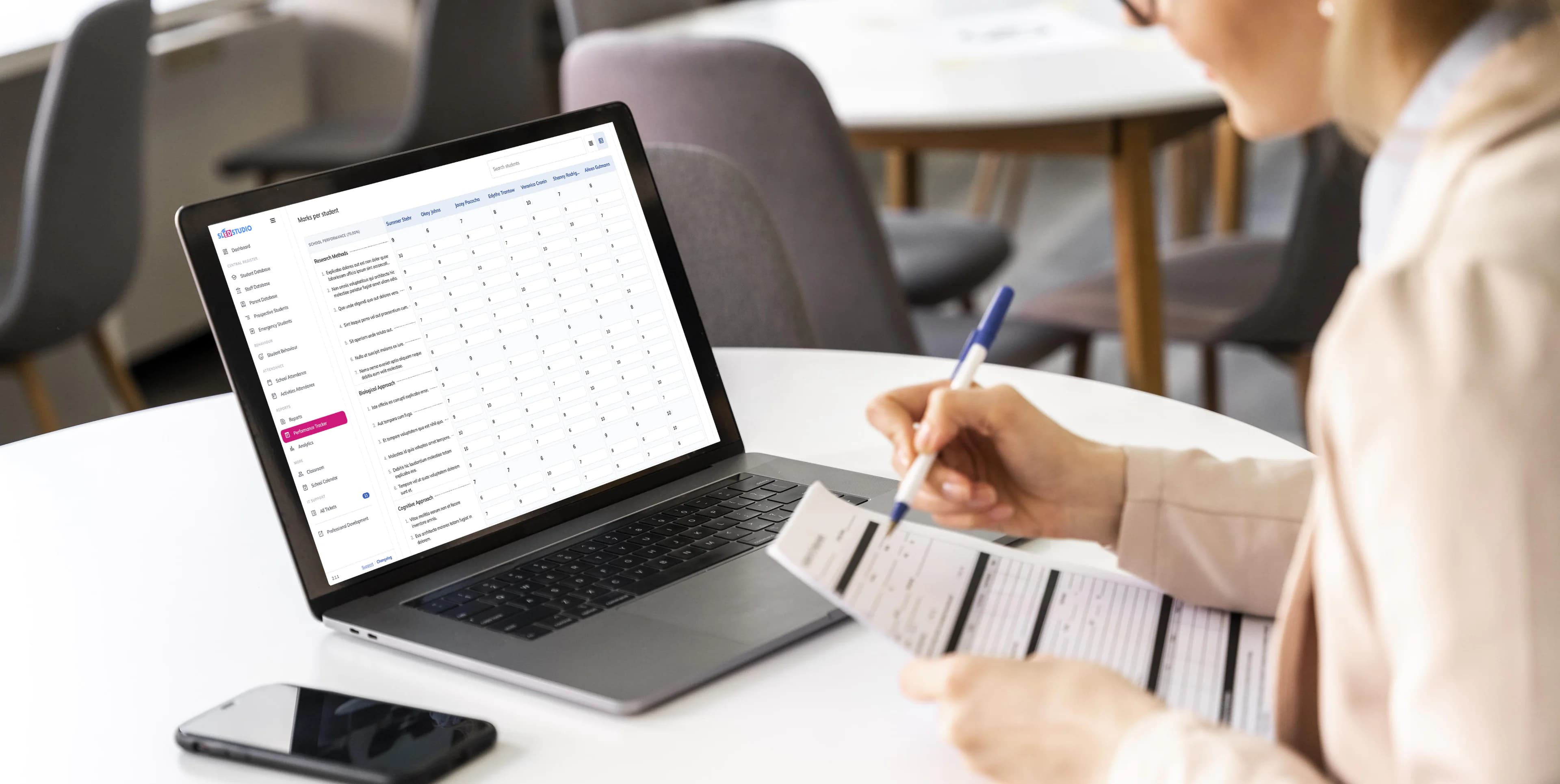 School staff member checking paper records against the platform on a laptop